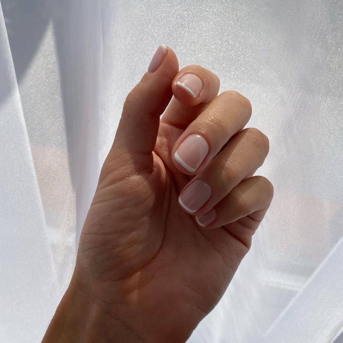 An image showing a short french tip manicure on @rosiehw