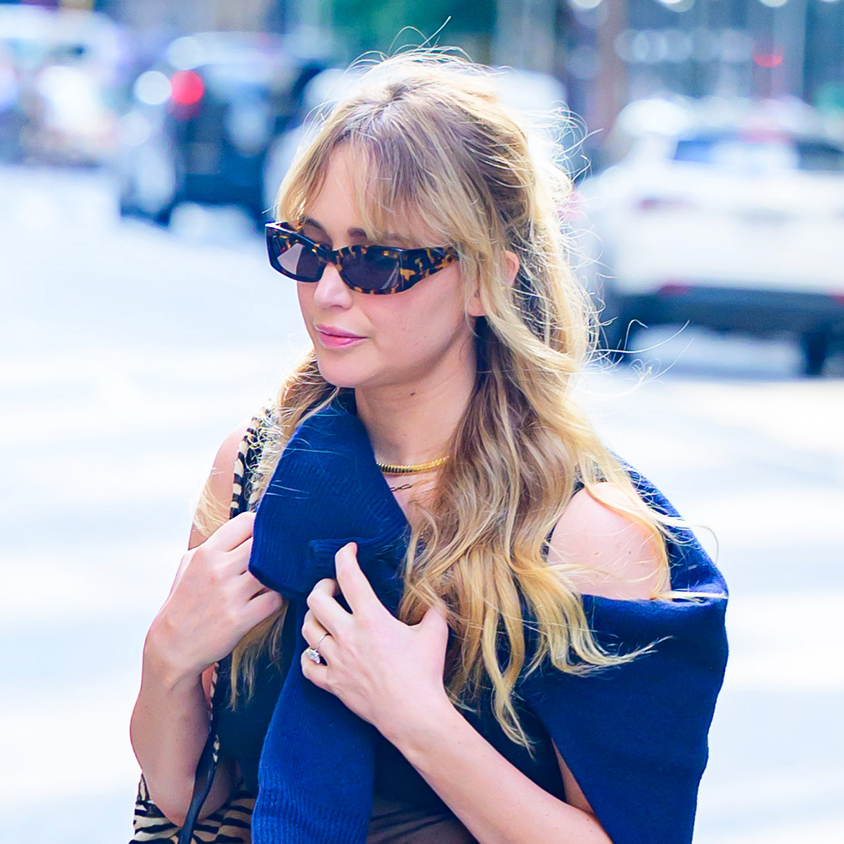 Jennifer Lawrence wearing a sweater around her shoulders and sunglasses