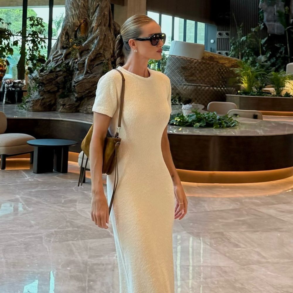Rosie Huntington-Whiteley wears a longline boucle t-shirt dress with a light khaki suede handbag, flip-flops and dark sunglasses.