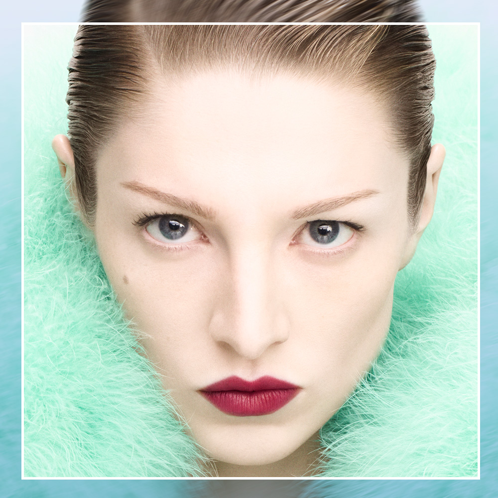 Hunter Schafer in a turquoise fluffy jacket wearing a bold red lipstick