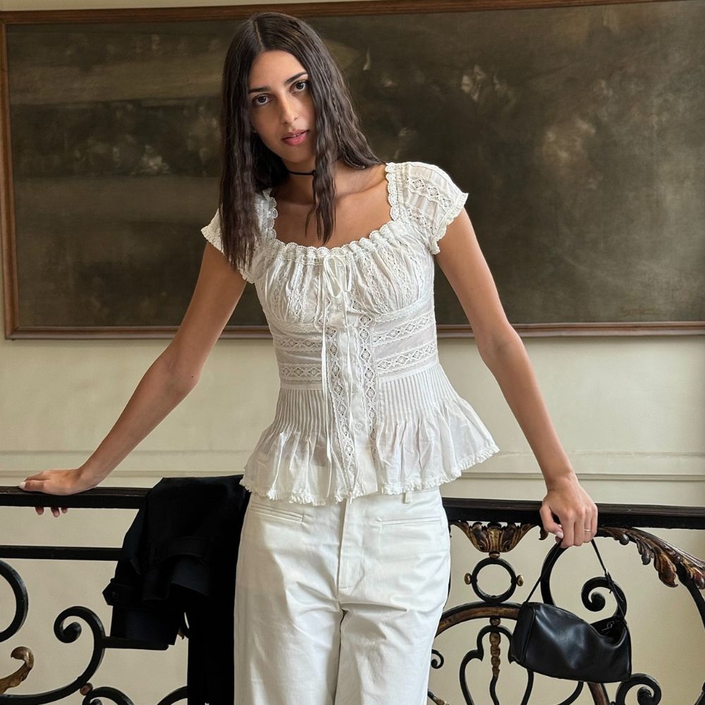 Influencer @salome.mory wears a white cotton blouse with white jeans and a carries a small black bag.