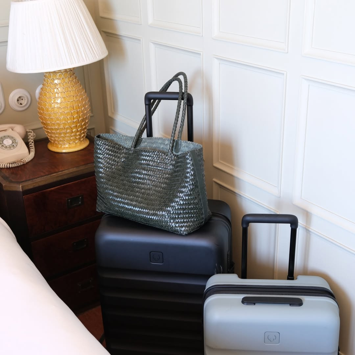 Two suitcases in a hotel room with a bag on top